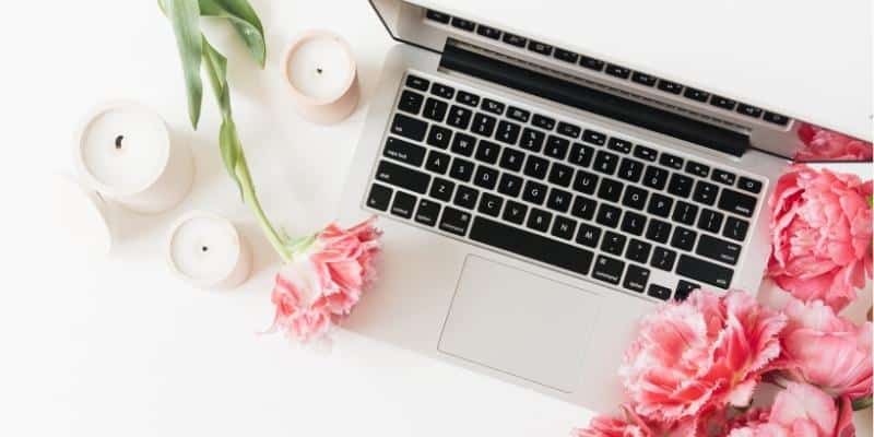 Laptop with pink flowers and white candles